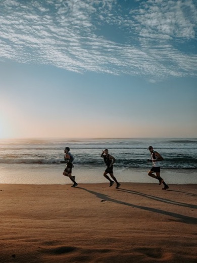 Three runners on a beach at golden hour