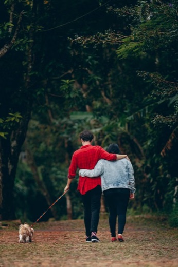 Couple walking their dog on a lush wooded path